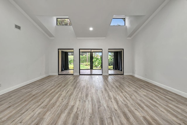 unfurnished room featuring high vaulted ceiling and light hardwood / wood-style floors