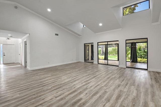 unfurnished living room with high vaulted ceiling, visible vents, light wood finished floors, and baseboards