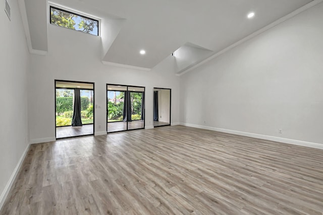 unfurnished room with french doors, crown molding, light hardwood / wood-style flooring, and a high ceiling