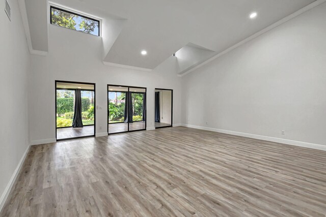 interior space with high vaulted ceiling, light wood finished floors, and baseboards