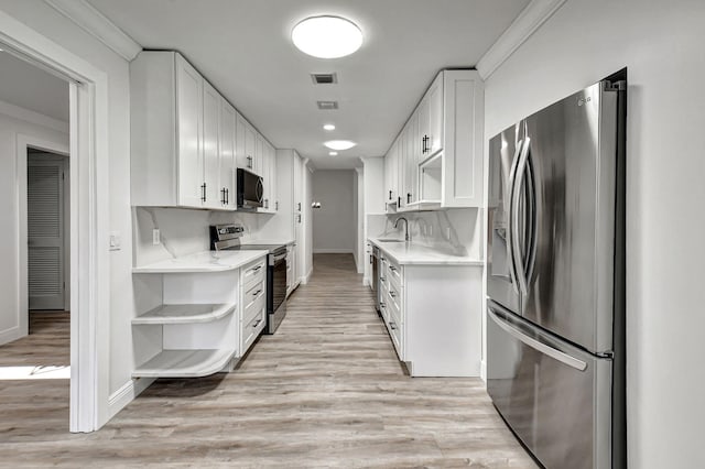 kitchen with white cabinets, sink, light hardwood / wood-style flooring, ornamental molding, and appliances with stainless steel finishes