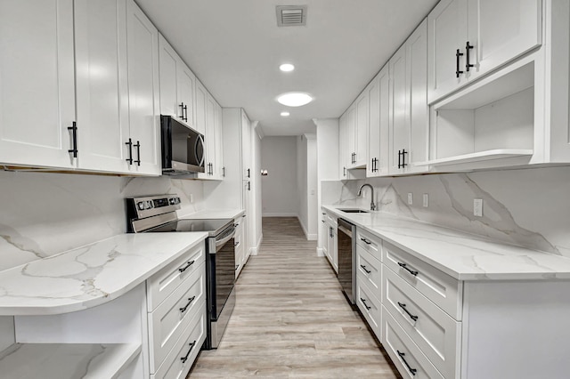 kitchen with white cabinets, light stone countertops, light wood-type flooring, and appliances with stainless steel finishes