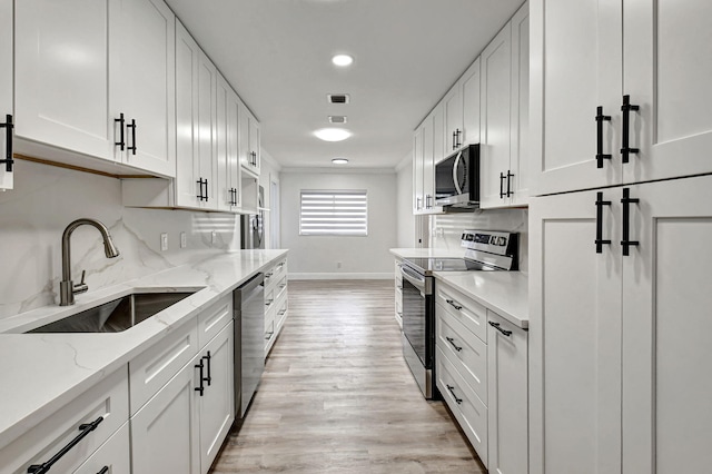 kitchen featuring white cabinets, light wood-type flooring, stainless steel appliances, and sink