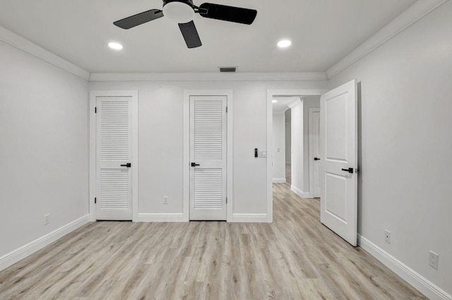 unfurnished bedroom featuring multiple closets, ceiling fan, ornamental molding, and light wood-type flooring