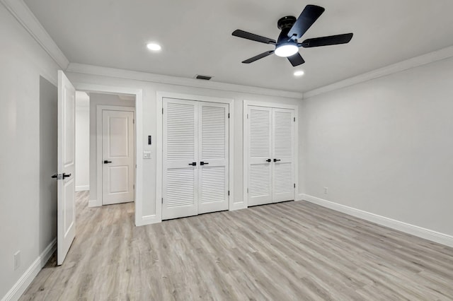 unfurnished bedroom featuring multiple closets, light wood-type flooring, ceiling fan, and crown molding