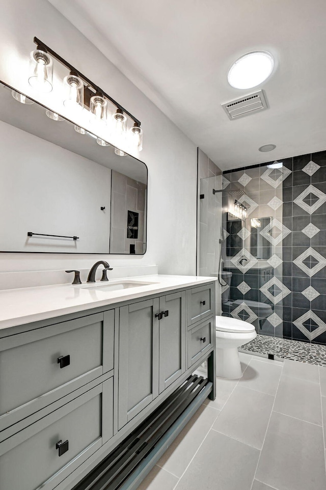 bathroom featuring tile patterned floors, vanity, toilet, and a shower with shower door