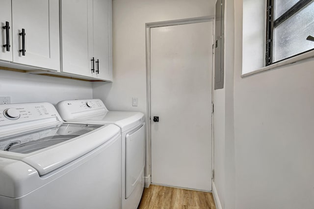 laundry area featuring electric panel, light hardwood / wood-style floors, cabinets, and washing machine and dryer