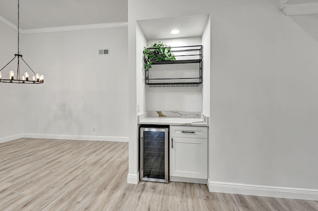 bar featuring wine cooler, white cabinets, hanging light fixtures, and light hardwood / wood-style floors