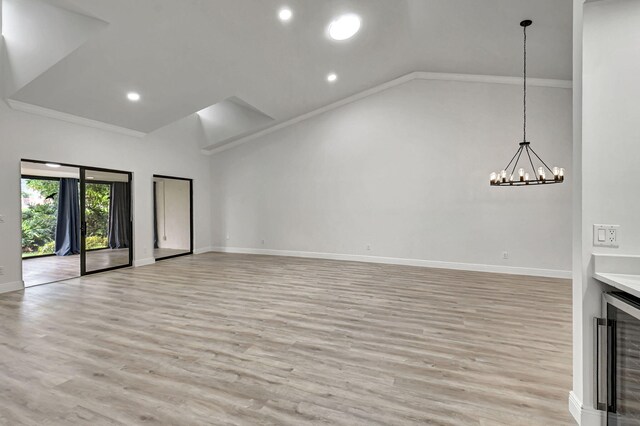 unfurnished living room with a chandelier, beverage cooler, ornamental molding, and baseboards