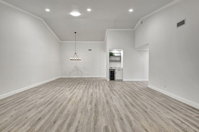 unfurnished living room featuring light wood finished floors, wine cooler, visible vents, and baseboards