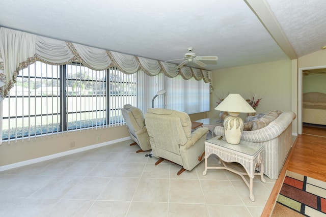 living room with ceiling fan, light tile patterned flooring, vaulted ceiling, and a textured ceiling