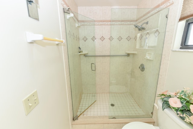 bathroom featuring toilet and a shower with door