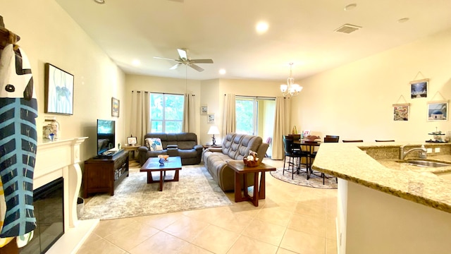 living room with sink, light tile patterned flooring, and ceiling fan with notable chandelier