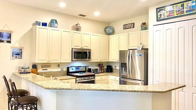 kitchen with light stone countertops, kitchen peninsula, and appliances with stainless steel finishes