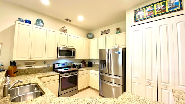 kitchen featuring light stone countertops, sink, light tile patterned floors, and appliances with stainless steel finishes