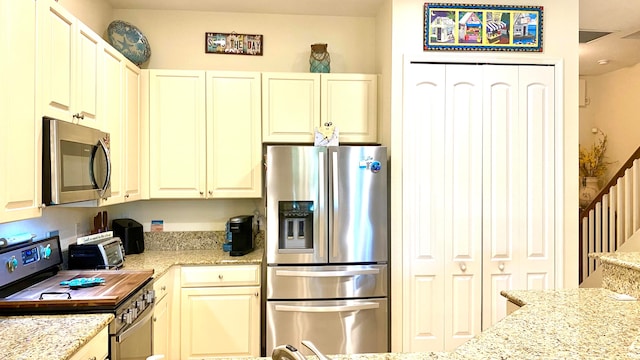 kitchen with light stone counters and appliances with stainless steel finishes