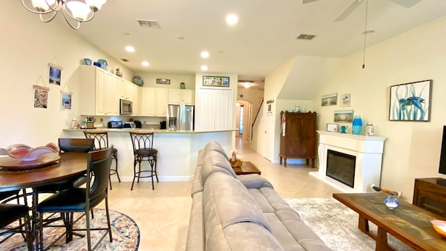 living room with light tile patterned floors and ceiling fan with notable chandelier