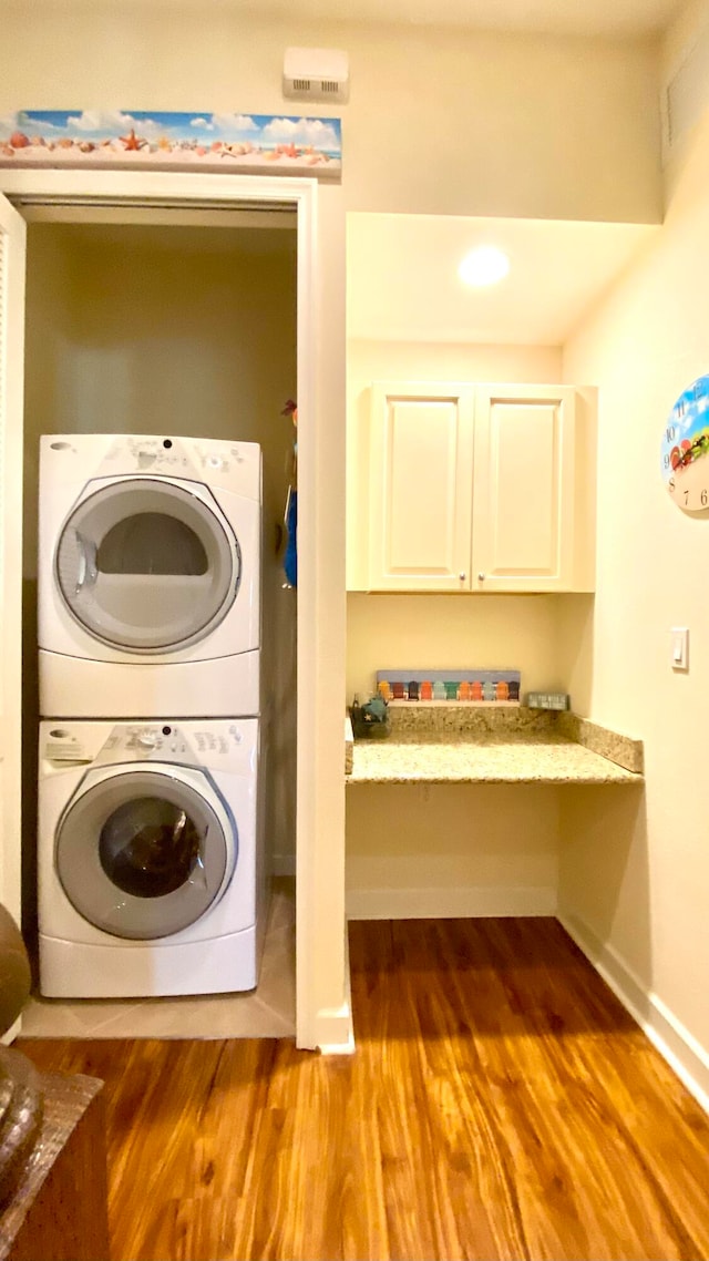 laundry area featuring hardwood / wood-style floors and stacked washer / drying machine