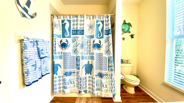 bathroom featuring walk in shower, hardwood / wood-style flooring, and toilet