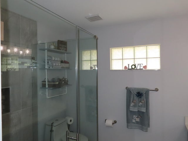 bathroom with a shower with door and toilet