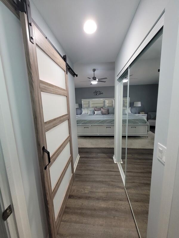 corridor with a barn door and dark wood-type flooring