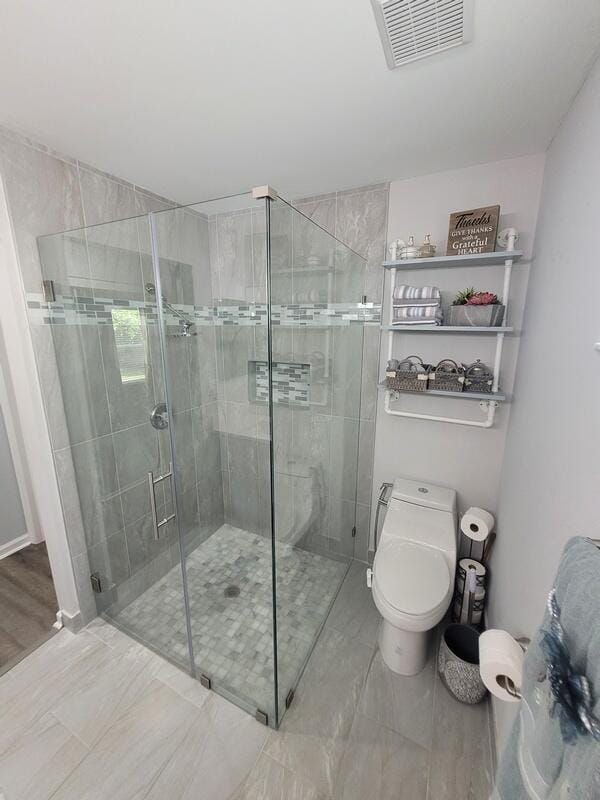 bathroom featuring walk in shower, wood-type flooring, and toilet