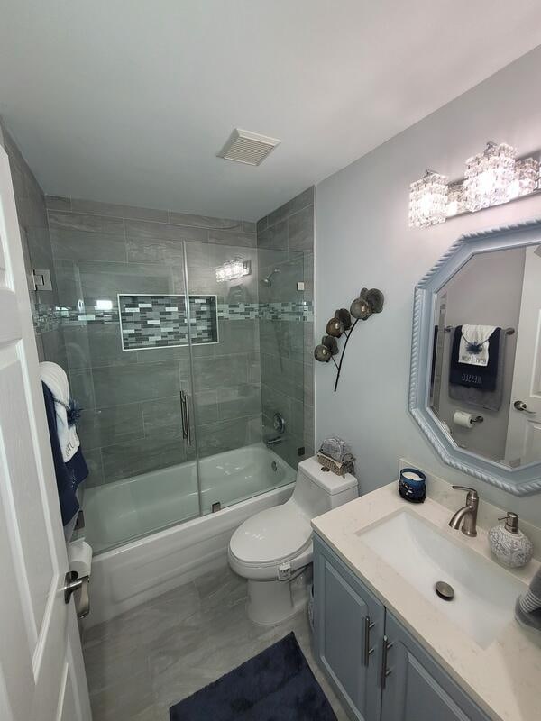 full bathroom with toilet, vanity, and combined bath / shower with glass door