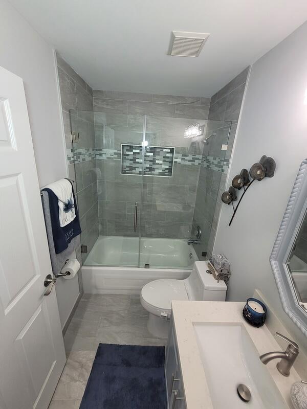 full bathroom with vanity, combined bath / shower with glass door, and toilet