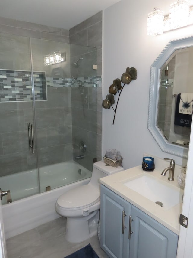 full bathroom with enclosed tub / shower combo, vanity, and toilet