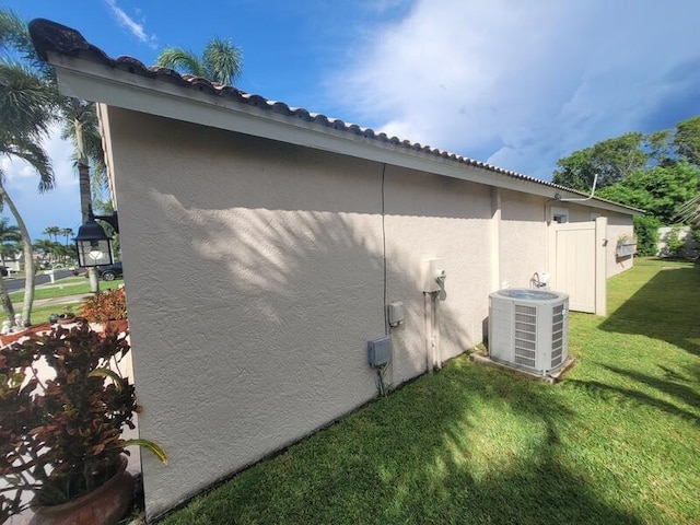 view of property exterior with central AC and a yard