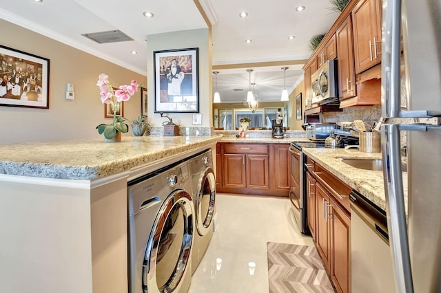 kitchen with hanging light fixtures, appliances with stainless steel finishes, tasteful backsplash, kitchen peninsula, and washing machine and clothes dryer