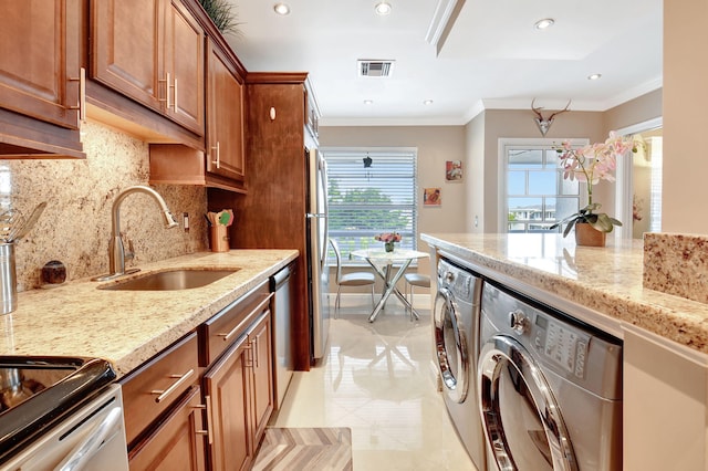 kitchen with light stone countertops, sink, washer and dryer, and ornamental molding