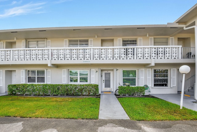 2721 SW 15th St Unit 203, Delray Beach, FL 33445 - view of front of property with a balcony, stucco siding, and a front yard