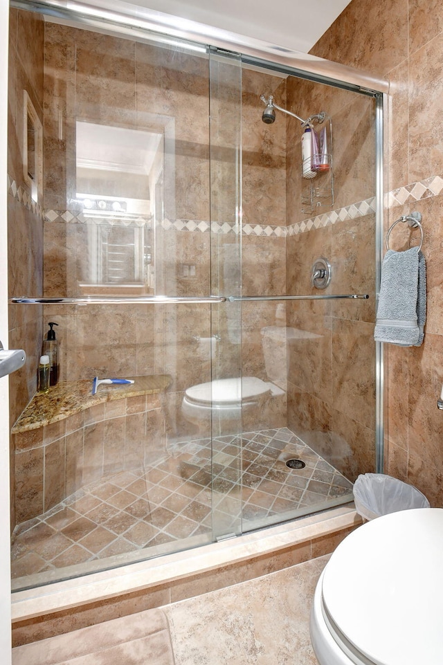 bathroom featuring toilet and a shower with shower door