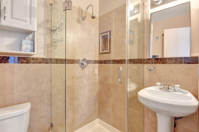 bathroom with an enclosed shower, toilet, and tile walls