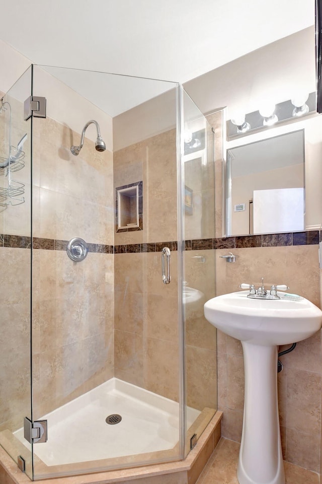 bathroom with a shower with door and tile walls