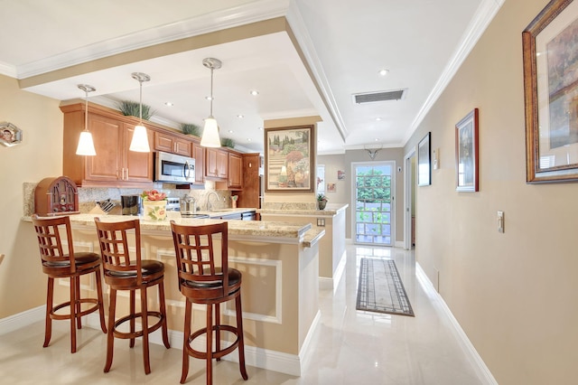 kitchen with hanging light fixtures, decorative backsplash, light stone countertops, a kitchen bar, and kitchen peninsula