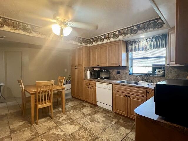 kitchen featuring decorative backsplash, dishwasher, ceiling fan, and sink