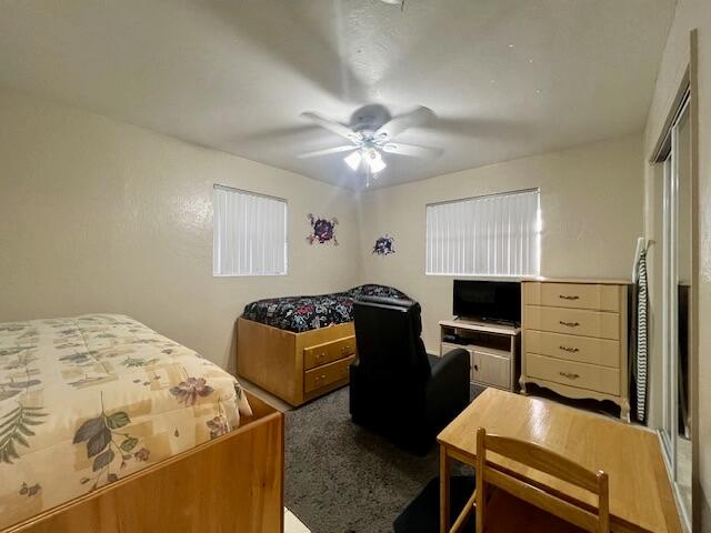 bedroom featuring dark carpet, a closet, and ceiling fan