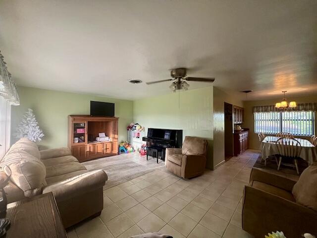 living room with ceiling fan with notable chandelier and light tile patterned floors