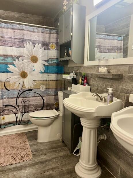 bathroom with wood-type flooring, curtained shower, and toilet