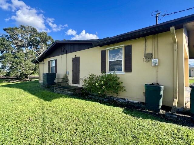 back of property featuring cooling unit and a yard