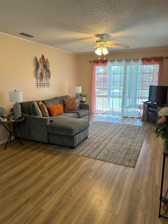 living room with ceiling fan, hardwood / wood-style flooring, a textured ceiling, and a wealth of natural light