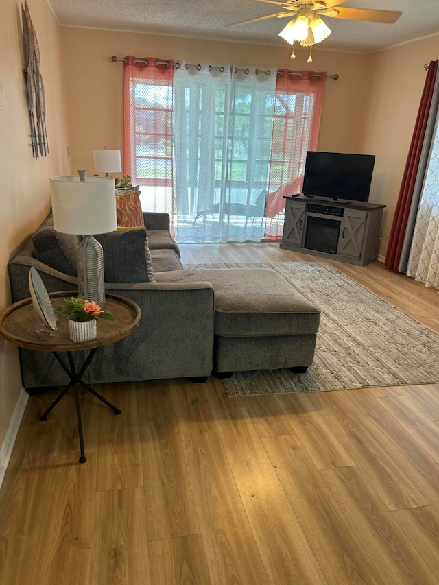 living room with a textured ceiling, wood-type flooring, and ceiling fan