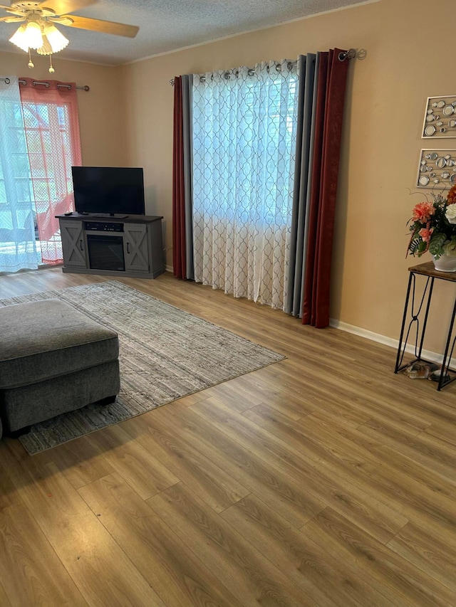 living room featuring ceiling fan, wood-type flooring, and a textured ceiling