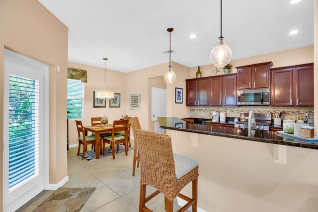 kitchen featuring pendant lighting, a kitchen bar, backsplash, and appliances with stainless steel finishes