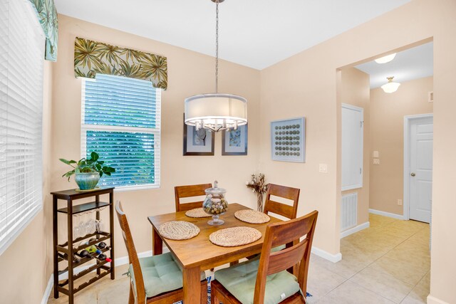 tiled dining room with a notable chandelier