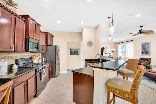 kitchen featuring appliances with stainless steel finishes, light tile patterned flooring, backsplash, pendant lighting, and sink