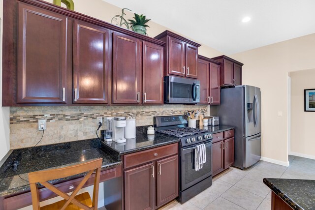 kitchen with stainless steel appliances, backsplash, light tile patterned floors, and dark stone counters