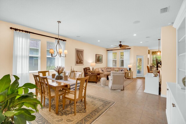 tiled dining area featuring ceiling fan with notable chandelier